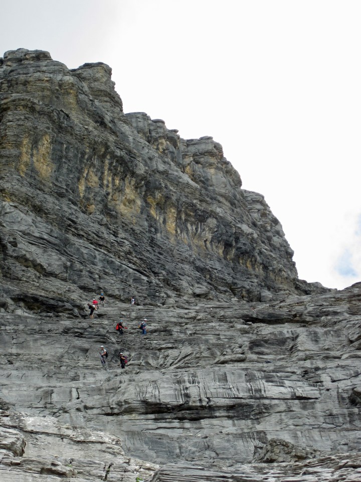 People zigzagging across the mountain as they descend from the Rotstock.