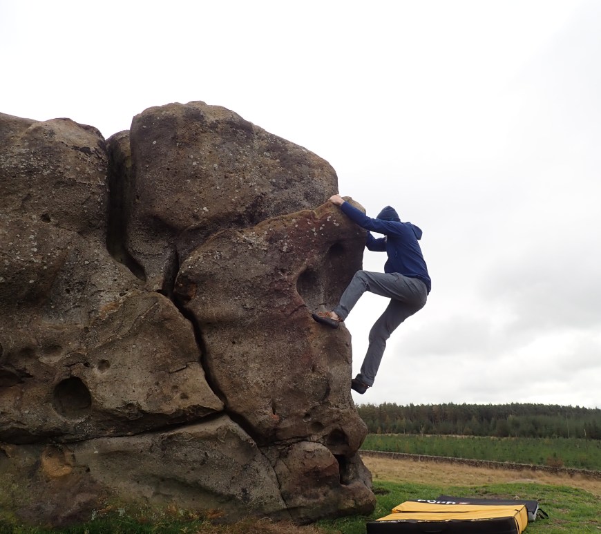 Climbing on an arete on High Man at Little Almscliff.